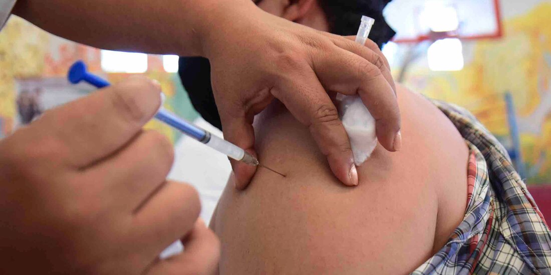 Personal de salud aplica una vacuna contra COVID-19 en el brazo izquierdo de un hombre que usa cubrebocas. La CDMX alista dosis de refuerzo para la población