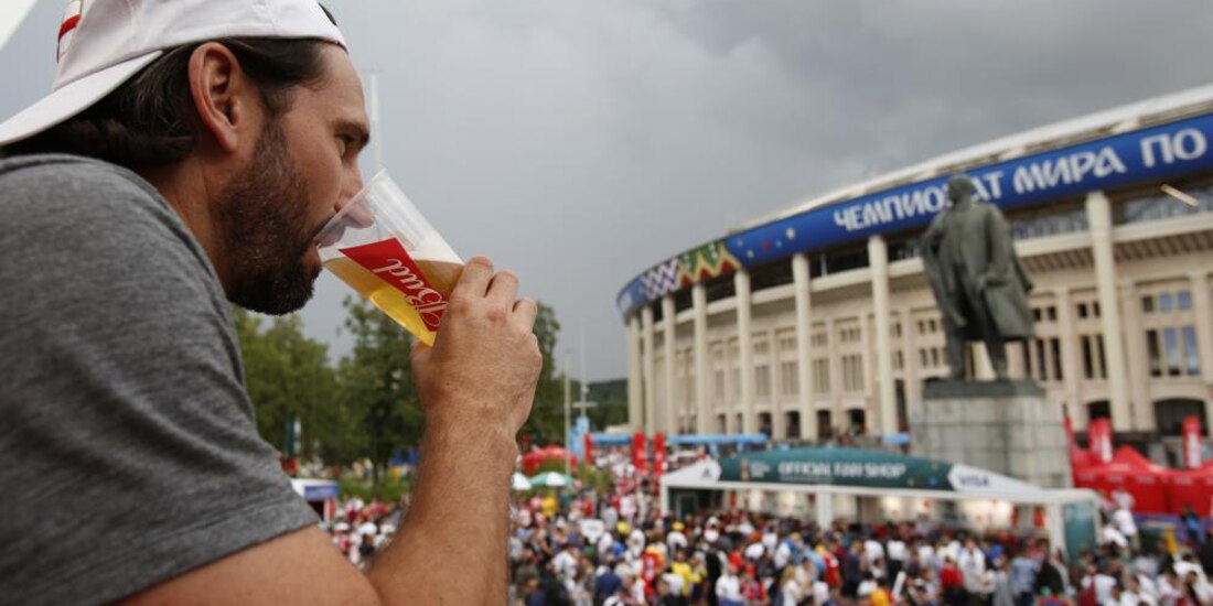 Hombre bebe una cerveza frente a la estatua de Lenin y el estadio Luzhniki, durante la Copa Mundial de futbol de 2018 en Moscú.