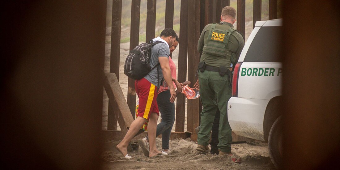 Pareja migrante cruza el muro fronterizo de Playas de Tijuana