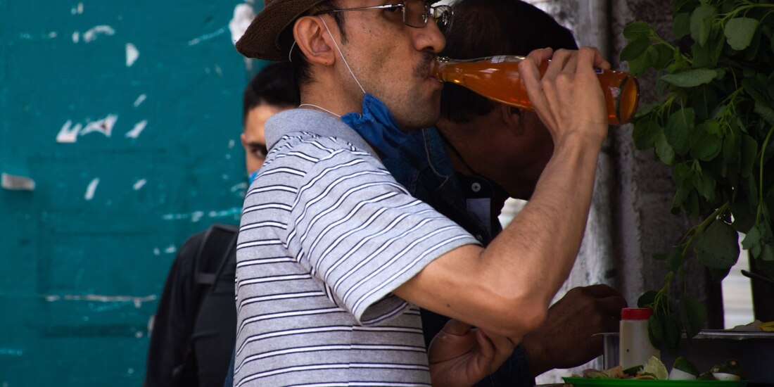Un hombre bebe un refresco mientras come en un local en la ciudad