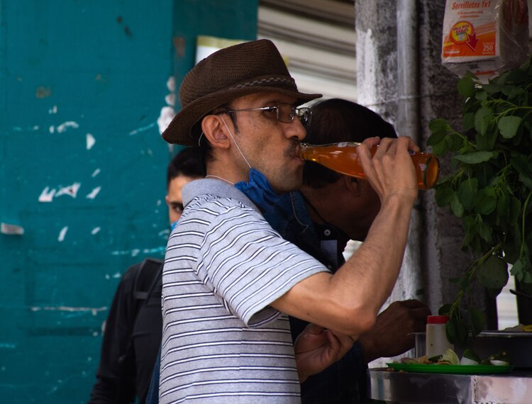 Un hombre bebe un refresco mientras come en un local en la ciudad