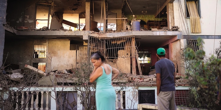 Los Residentes observan un complejo de apartamentos dañado, ayer.
