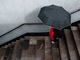 Una persona con paraguas ingresa a una estación del Metro en un día de lluvia