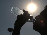 A contra luz, un hombre toma agua de una botella para mitigar el calor