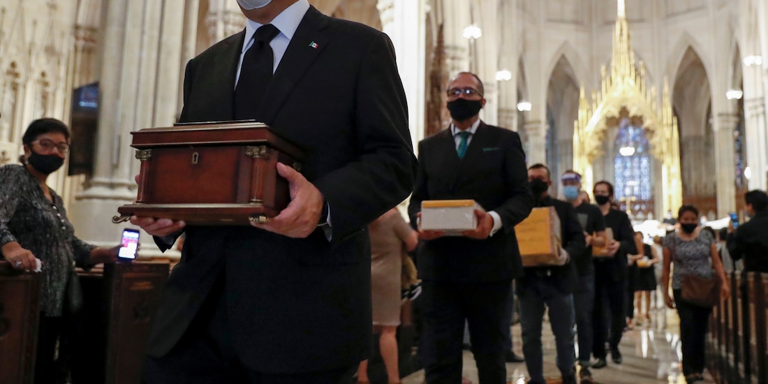 El cónsul de México en Nueva York, Jorge Islas, encabeza una fila de gente en la Catedral de San Patricio, en Manhattan, que carga las cenizas de mexicanos muertos en EU durante la pandemia.