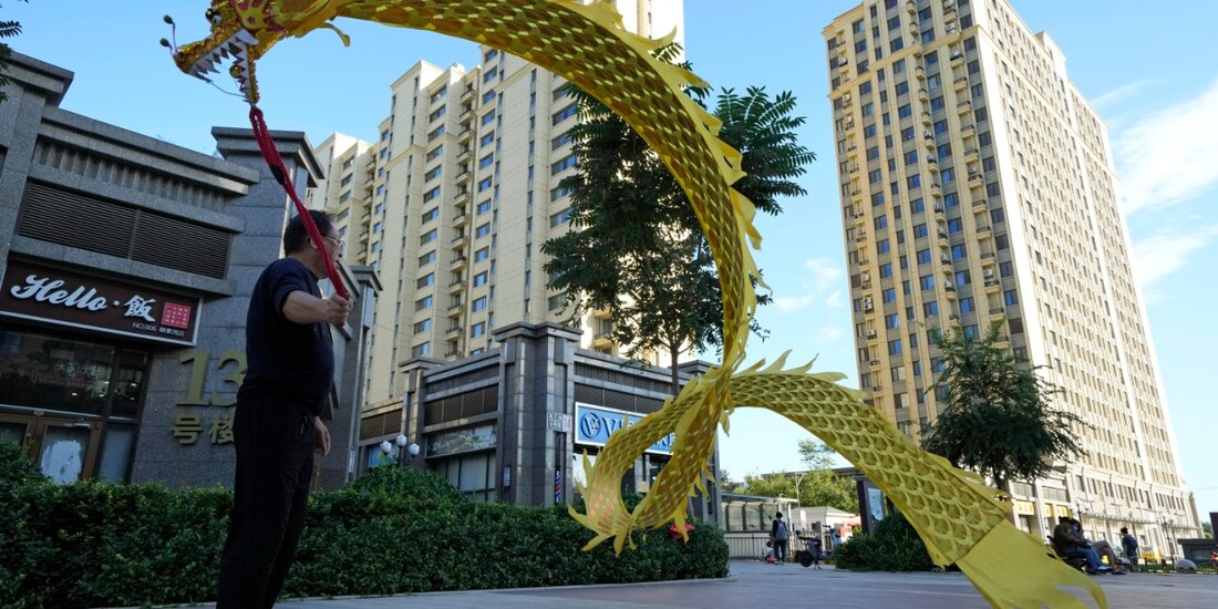 Un hombre ondea un dragón de tela ante el complejo residencial Evergrande Yujing Bay en Beijing, China.