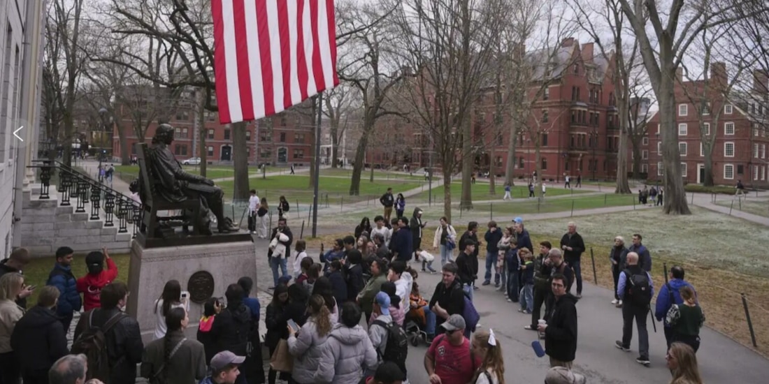 Visitantes frente a la figura de Harvard en la Universidad.