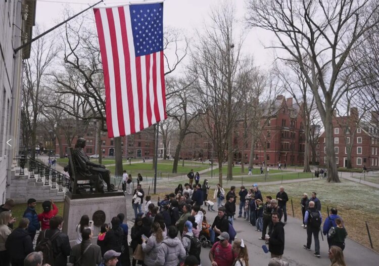 Visitantes frente a la figura de Harvard en la Universidad.