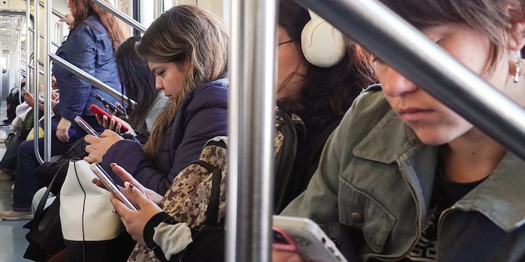 Usuarias del Metro al revisar sus celulares durante su trayecto, ayer.