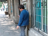 Un hombre fuma en una barda pintada con consignas contra Airbnb, en 2025.