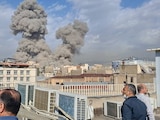 Personas observan cómo el humo se eleva en el horizonte después de una explosión en Teherán, Irán, el sábado 28 de febrero de 2026.