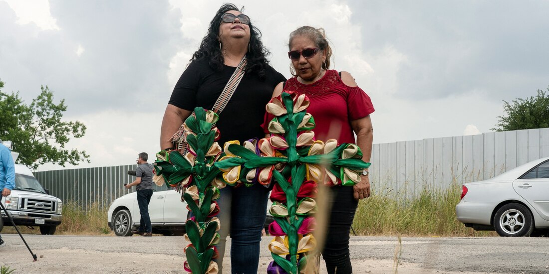 Personas lloran después de colocar cruces y velas en el lugar donde decenas de personas fueron encontradas muertas dentro de un tráiler en San Antonio, Texas.