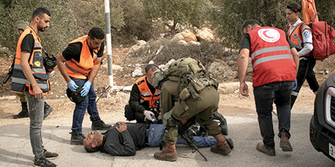 Médicos palestinos y un soldado israelí atienden a un herido, ayer, en Abu Falah.