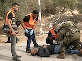 Médicos palestinos y un soldado israelí atienden a un herido, ayer, en Abu Falah.