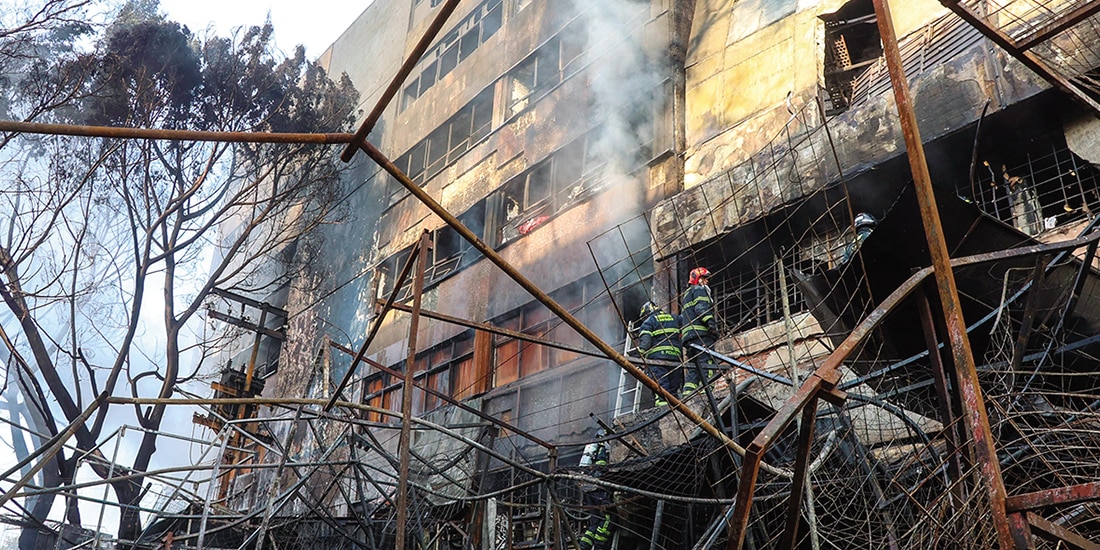 Bomberos laboran para apagar las llamas junto al mercado, ayer.