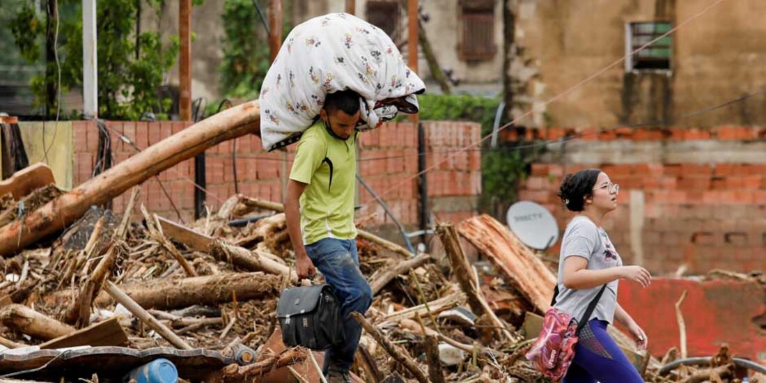 Una persona lleva sus pertenencias tras las inundaciones debidas a las fuertes lluvias, en Tejerias, estado Aragua, Venezuela