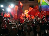 Simpatizantes del PSOE ondean banderas del actual partido en el gobierno tras la jornada electoral, ayer.