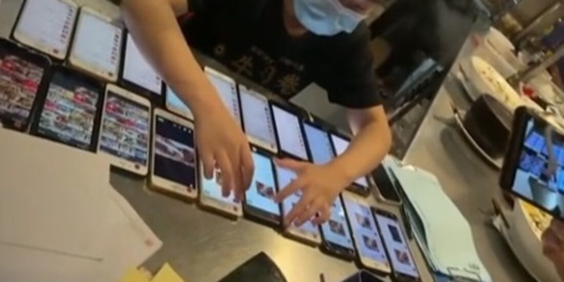 Empleada de restaurante en China trabaja con 20 celulares casi a la vez