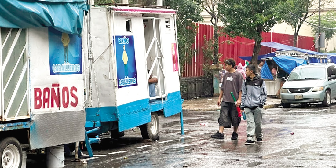 Dos hombres acuden a unos baños improvisados en una camioneta, ayer.
