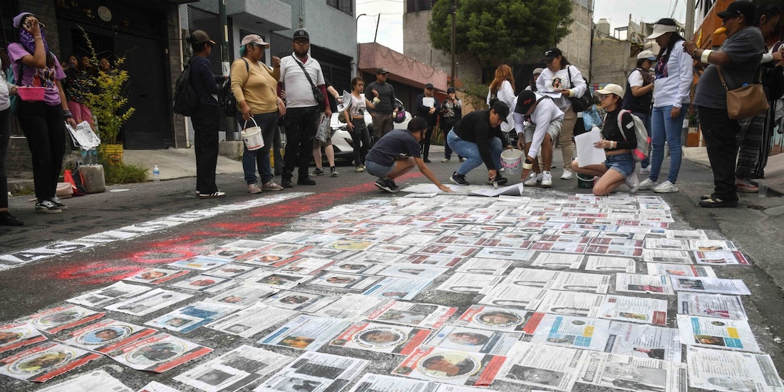 Integrantes de colectivos de búsqueda llevan a cabo una pega de fichas de personas desaparecidas, en Ciudad de México.