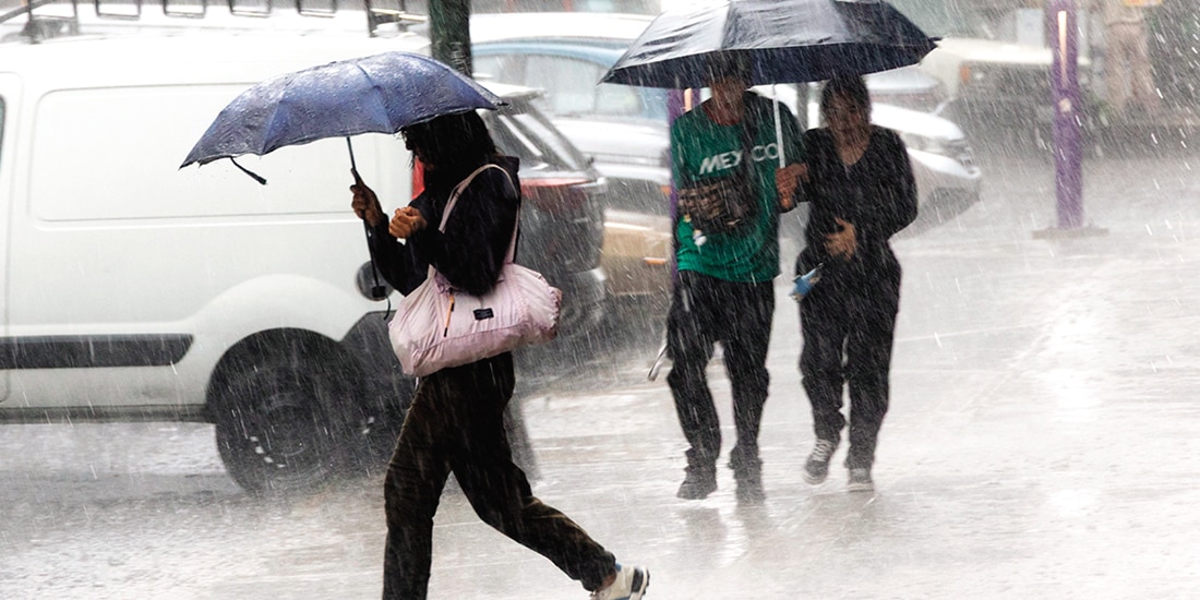 Habitantes de la capital se protegen de la fuerte precipitación, ayer.
