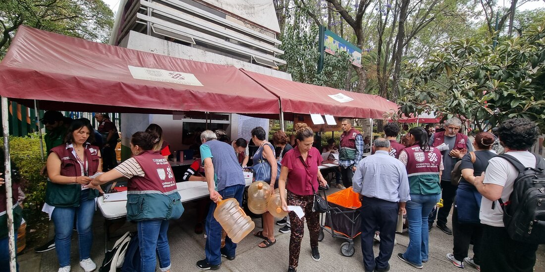 Vecinos hacen fila para tomar garrafones del gobierno, ayer.