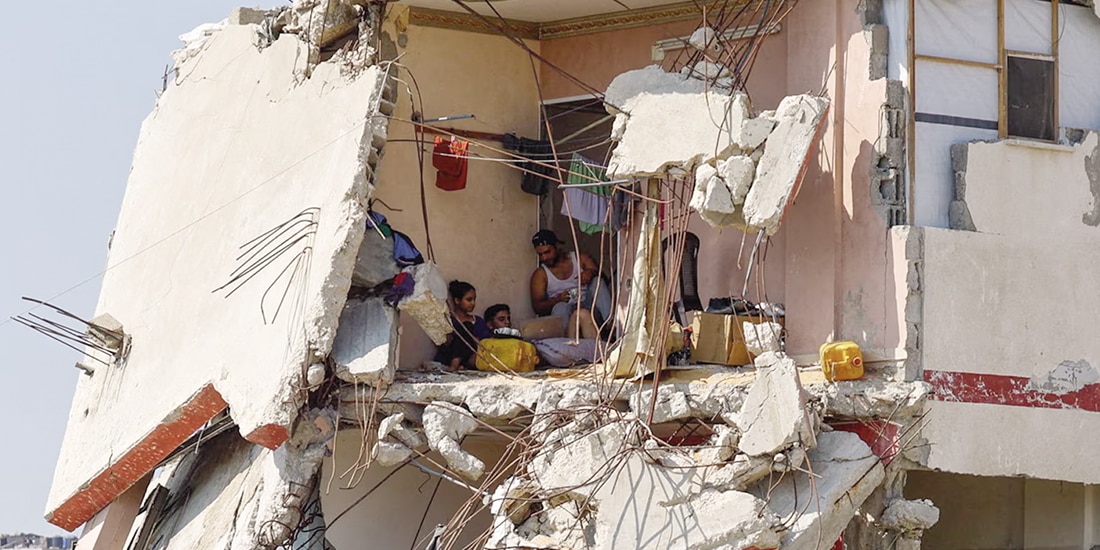 Palestinos se sientan dentro de una casa dañada durante la guerra en Gaza, ayer.