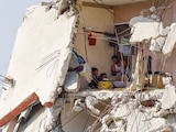 Palestinos se sientan dentro de una casa dañada durante la guerra en Gaza, ayer.