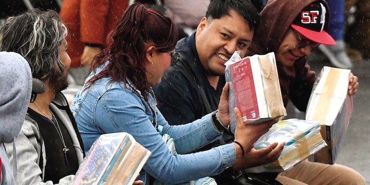 Personas, al recibir sus paquetes de libros gratuitos, ayer.