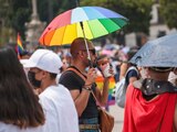 Un joven con una sombrilla multicolor toma una bebida durante la Marcha LGBT+ de este sábado en la CDMX