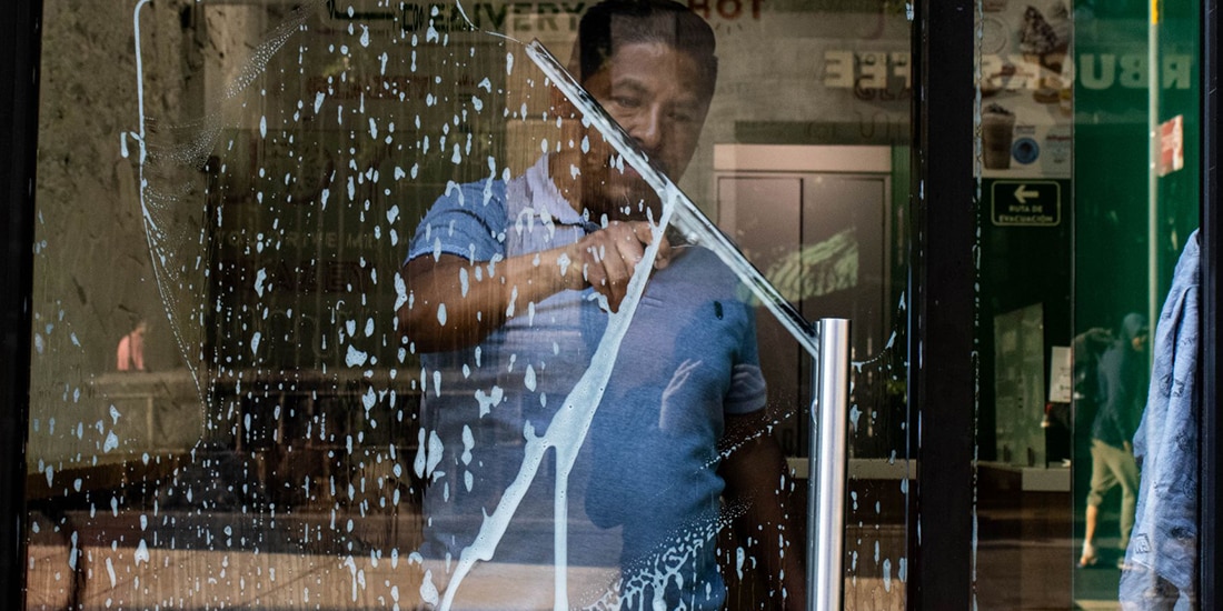 Un trabajador limpia los vidrios de un local comercial en el Centro Histórico.