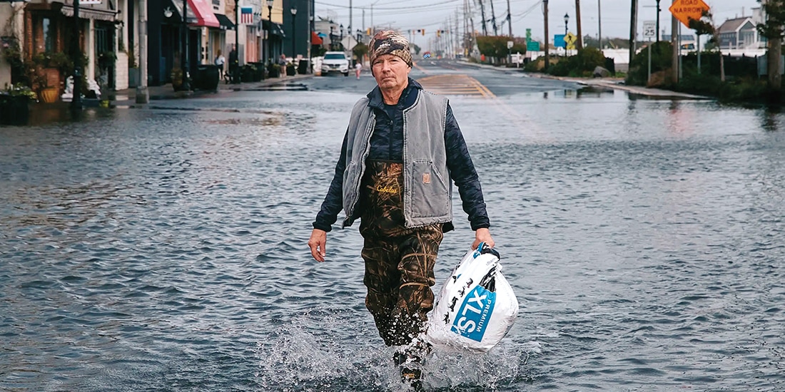 Un residente camina por una calle inundada tras una tormenta, ayer.