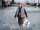 Un residente camina por una calle inundada tras una tormenta, ayer.
