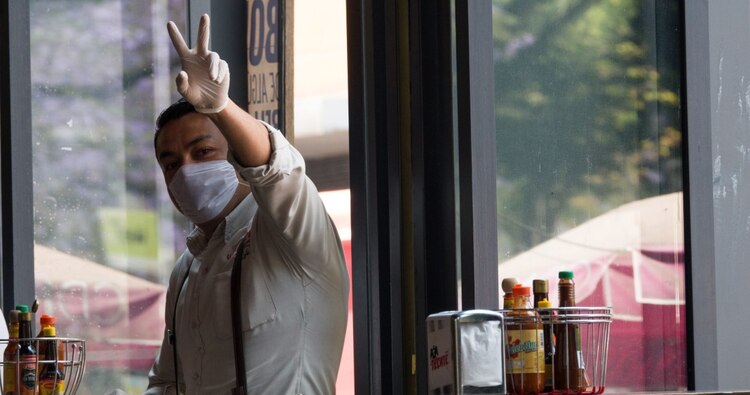 Mesero usa cubrebocas para evitar propagación de COVID-19