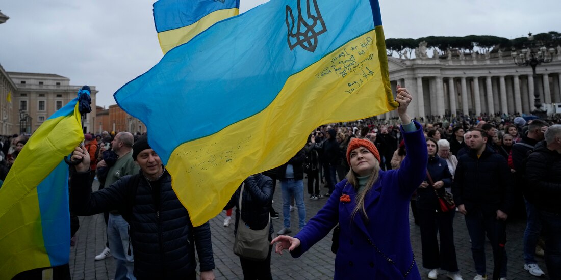 Fieles católicos ondean una bandera ucraniana en la Santa Sede, ayer, tras el mensaje del Papa en torno a la guerra.