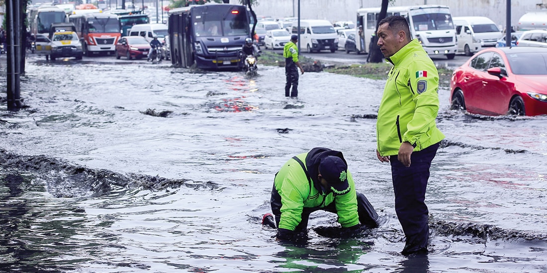 Dos policías trabajan para destapar una coladera de Zaragoza, el 3 de junio.