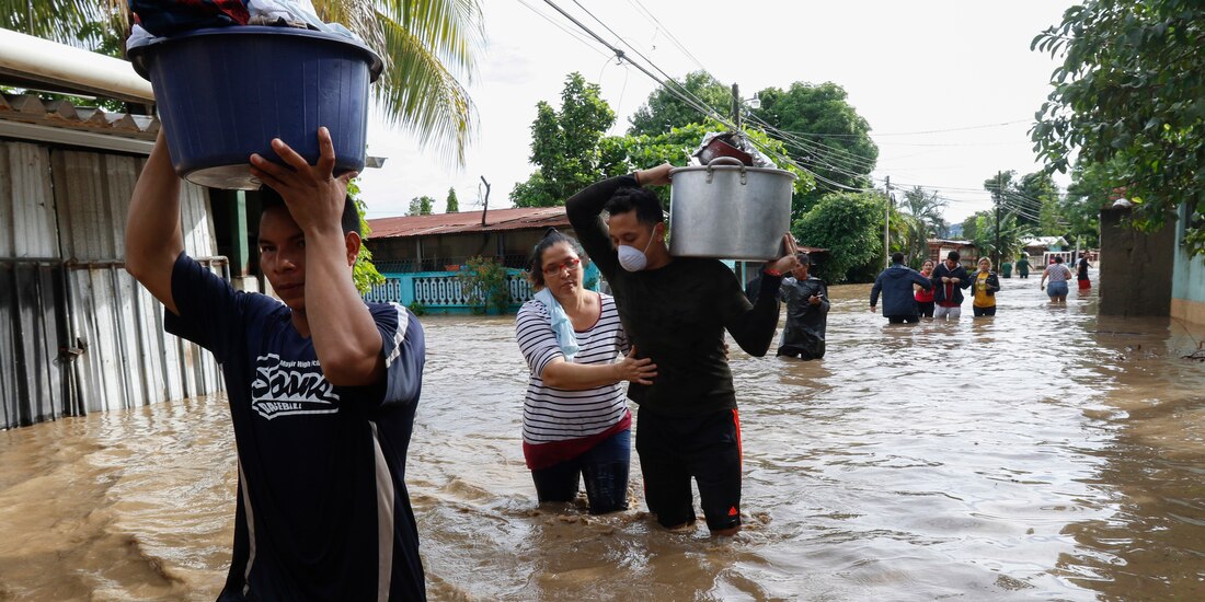 Los residentes caminan a través de las inundaciones cargando sus pertenencias en el vecindario de Suyapa, Honduras, el jueves 5 de noviembre de 2020.