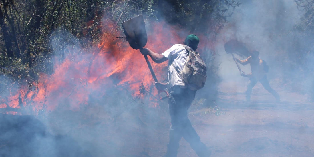 En la imagen de archivo, dos personas tratan de contener un incendio forestal