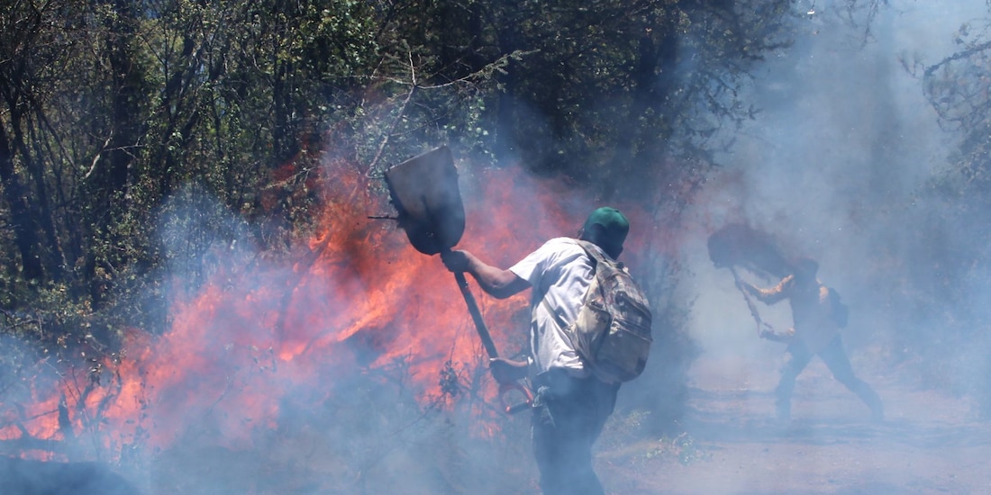 En la imagen de archivo, dos personas tratan de contener un incendio forestal