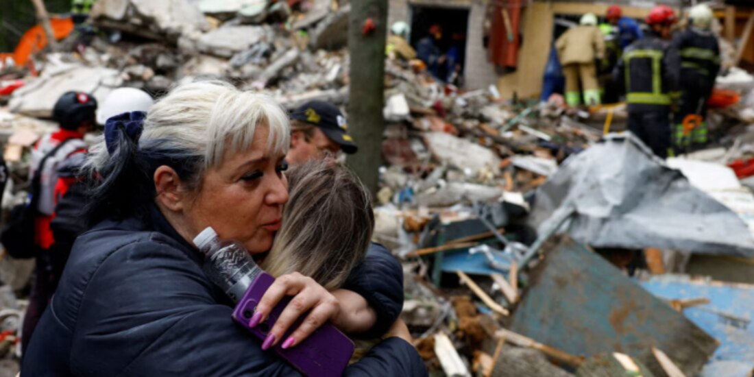 Una mujer abraza a una persona mientras espera que rescaten a su hijo debajo de los escombros, en Kiev, ayer.