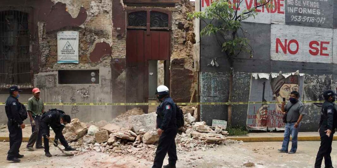 Un policía remueve restos de una barda, ayer, en Oaxaca.