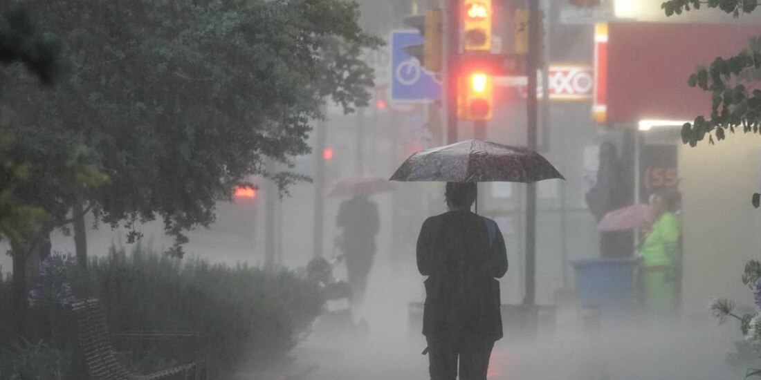 Una persona camina por la calle protegiéndose de la lluvia con un paraguas