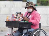 Una mujer en silla de ruedas vende cigarros y golosinas. Utiliza un cubrebocas para protegerse del COVID-19