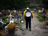 Músico camina entre tumbas en panteón en México