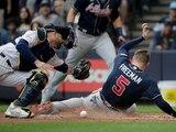 Freddie Freeman, de los Braves, anota más ante el receptor de los Brewers, Manny Pina, durante la tercera entrada.