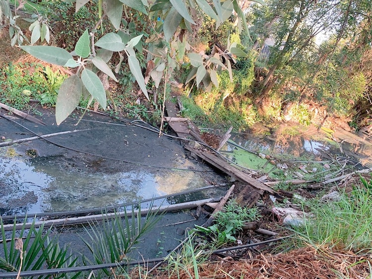 En esta parte de un canal semiseco se aprecian restos de un puente, piedras y basura.