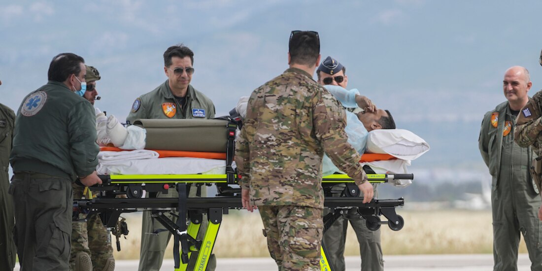 Personal militar de Grecia transporta en camilla a una persona herida, ayer.