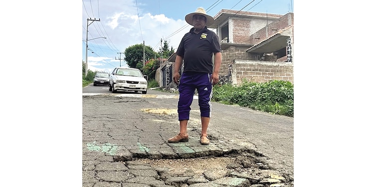 Genaro plazas parado a un lado del asfalto dañado de una vialidad.