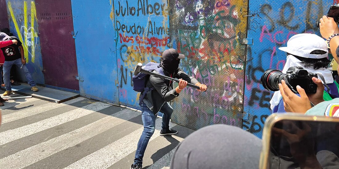Un encapuchado golpea una valla, el pasado lunes.