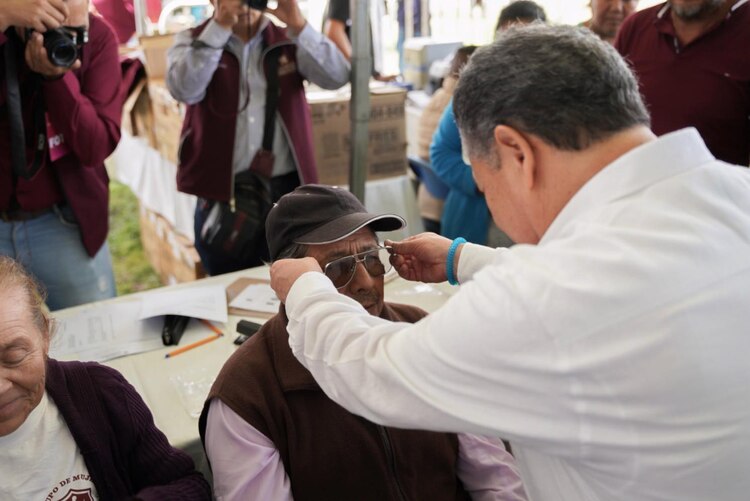 Julio Menchaca prueba unos lentes a un adulto mayor en una Feria de Servicios.